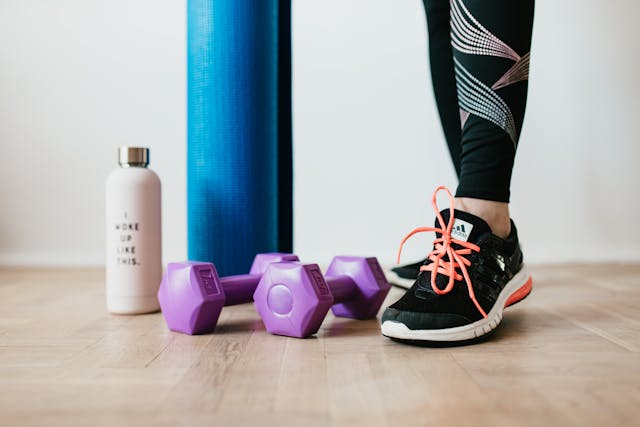 Unrecognizable female athlete standing near sport accessories.